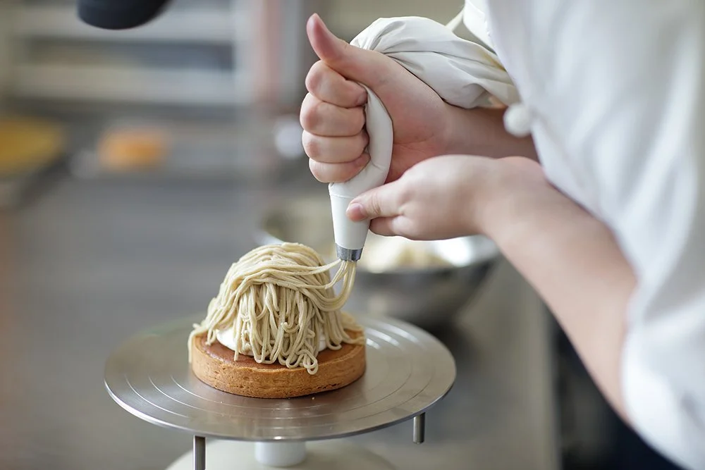 クリームで飾り付けするパティシエの手元